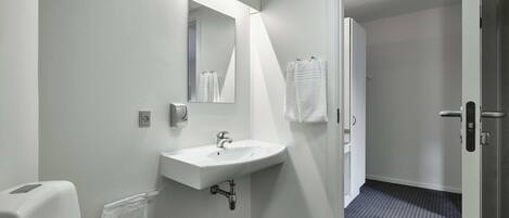 A bathroom with a white sink, a mirror, and a towel rack.