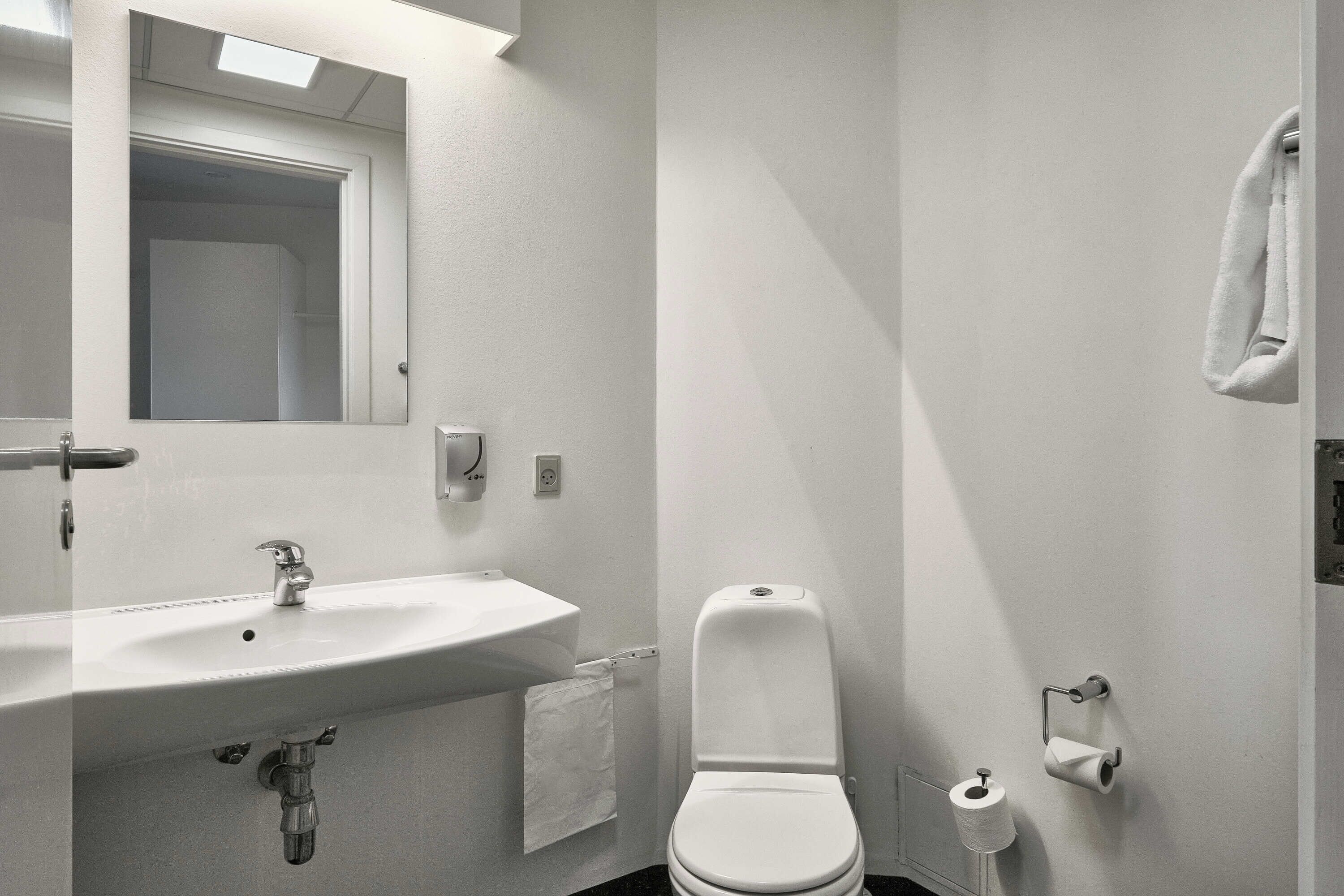 Et badeværelse med vask, toilet og håndklædestang.
