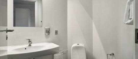 Un baño con lavabo, inodoro y perchero para toallas.