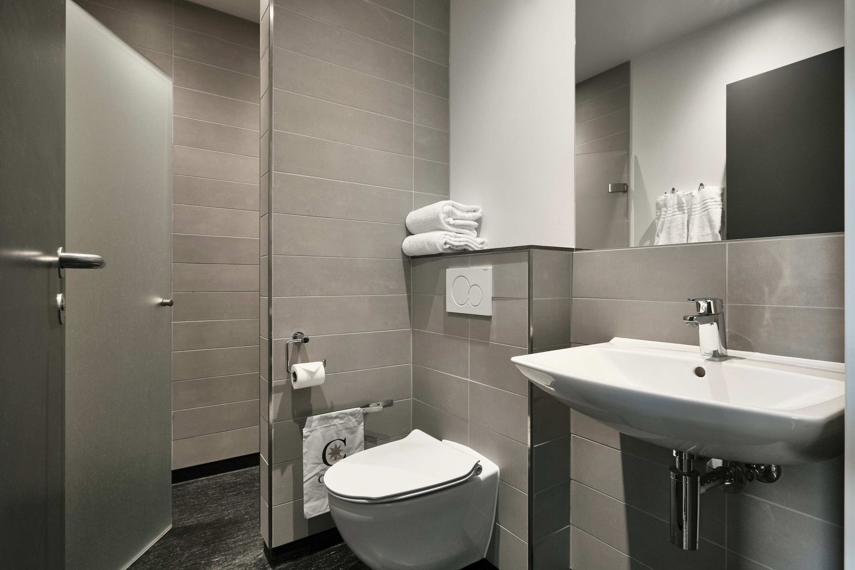 A modern bathroom with a toilet, sink, and towel rack.