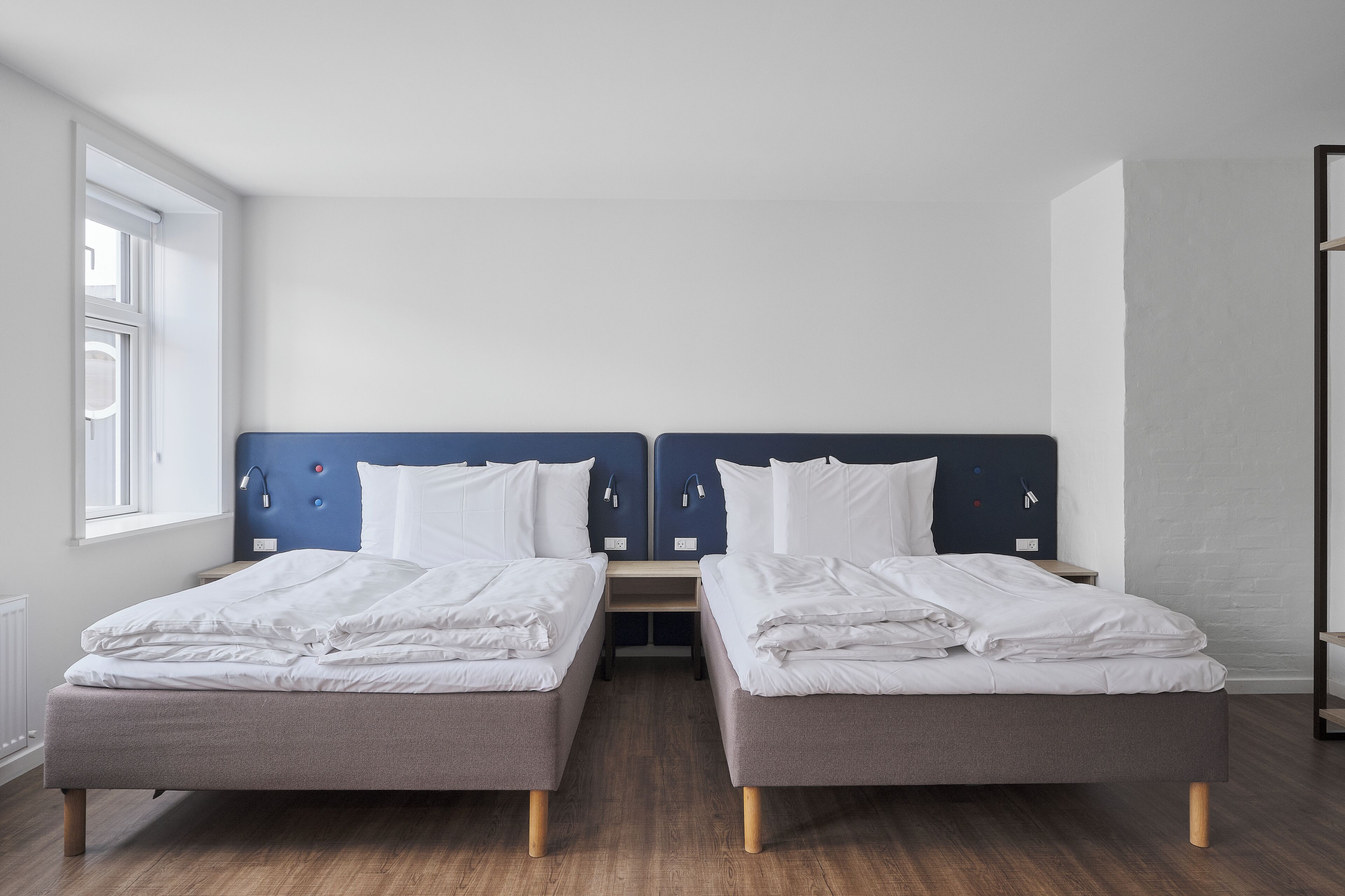 A double room with two beds, a nightstand, and a window.