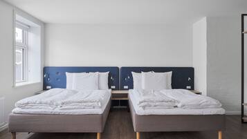 A double room with two beds, a nightstand, and a window.
