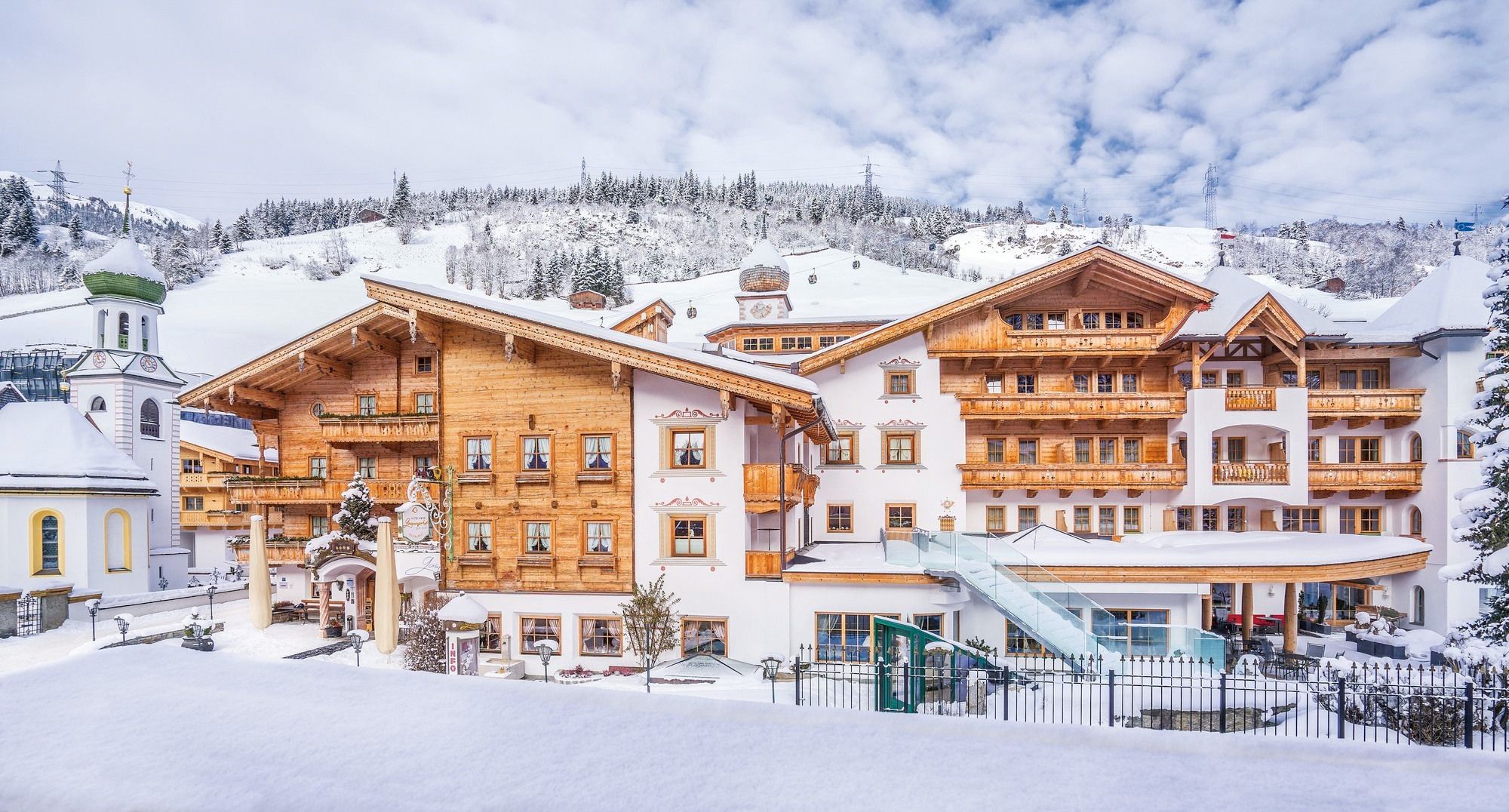 A large wooden hotel with multiple balconies and a ski lift visible in the background.