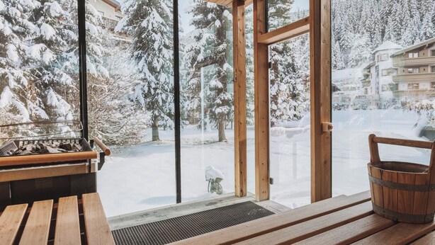 A wooden bench and table inside a building with large windows overlooking a snowy landscape. - Hotel Gaspingerhof (Gerlos)