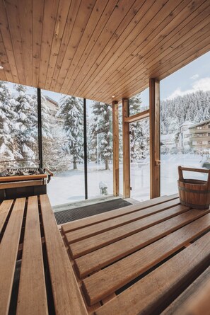 A wooden bench and table inside a building with large windows overlooking a snowy landscape. - Hotel Gaspingerhof (Gerlos)