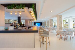 Un área de bar moderna con una barra larga, taburetes y una pantalla grande.