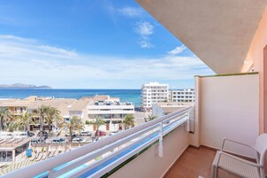 Un balcón con vista al mar y edificios.