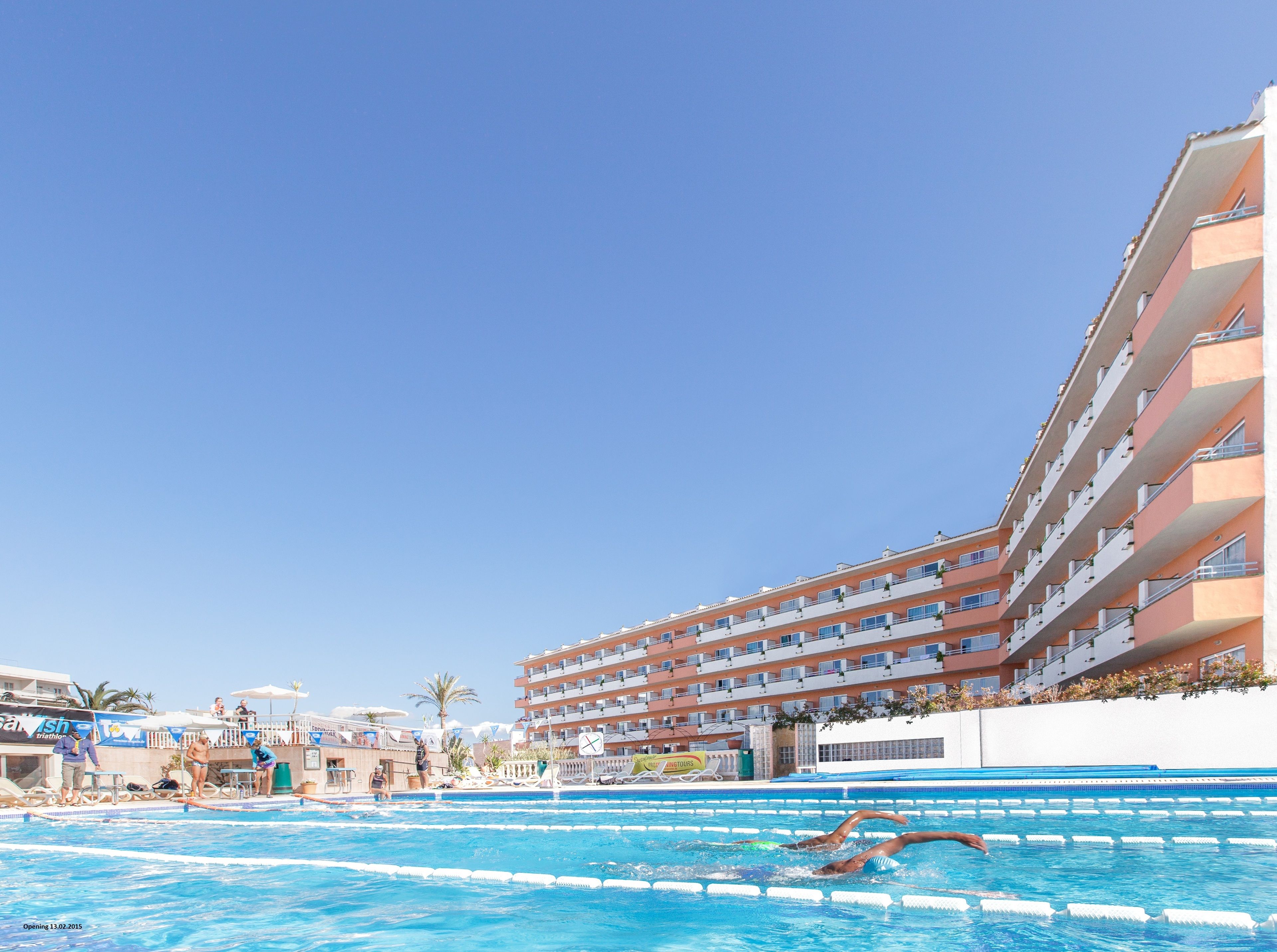 A swimming pool with multiple lanes, adjacent to a multi-story hotel with balconies.