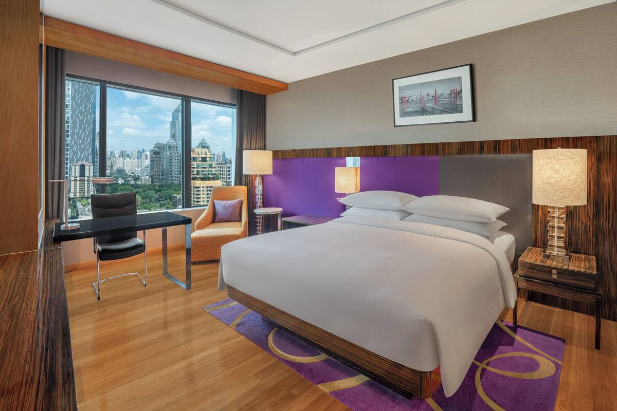 A modern hotel room with a large bed, a desk, and a chair.