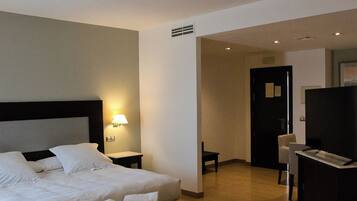 Una habitación de hotel con cama, mesita de noche, lámpara y escritorio con silla.