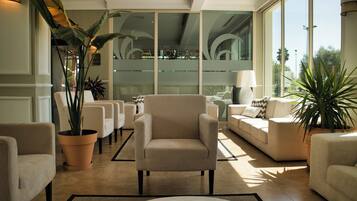 A modern interior with a seating area, large windows, and potted plants.