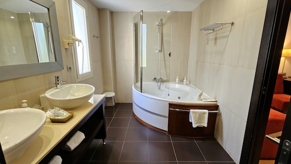 A modern bathroom with a large bathtub, a double sink vanity, and a glass-enclosed shower. - Hotel Las Bovedas (Badajoz)