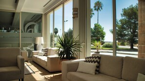 A modern living room with a sofa, armchair, and a large potted plant. - Hotel Las Bovedas (Badajoz)
