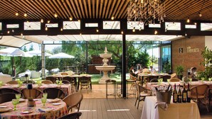 An outdoor dining area with tables, chairs, and a fountain. - Hotel Las Bovedas (Badajoz)