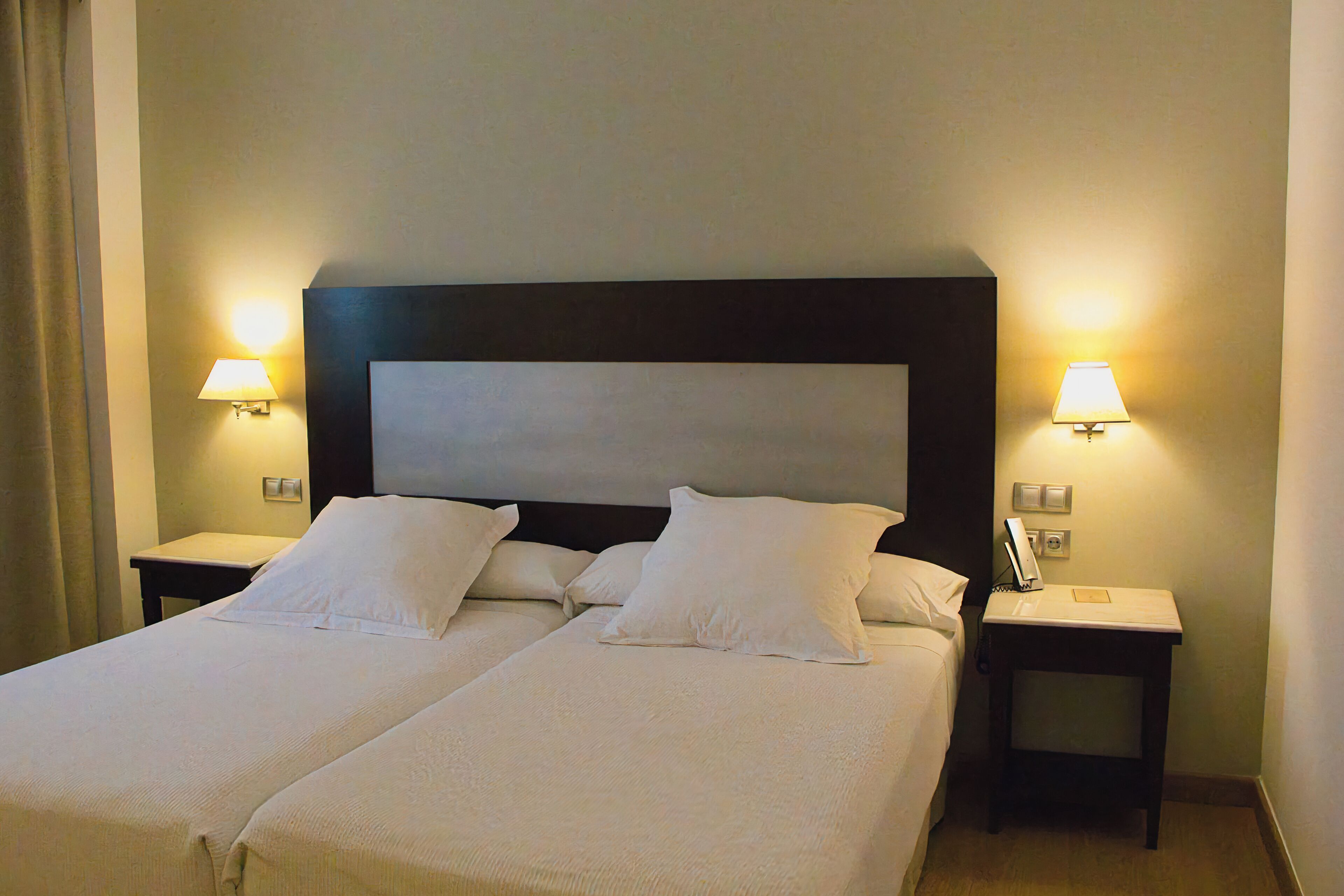 A double bed with two nightstands, each with a lamp and a phone.