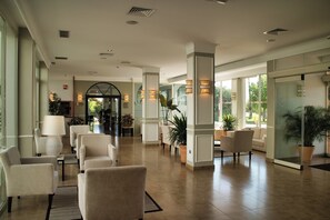 A spacious lobby with multiple seating areas, large windows, and potted plants. - Hotel Las Bovedas (Badajoz)