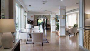 A spacious lobby with a reception desk, seating area, and a view of the street. - Hotel Las Bovedas (Badajoz)