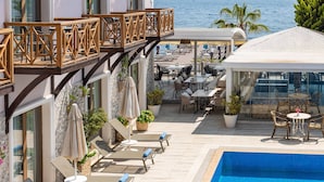 A hotel with a pool, outdoor seating, and a view of the sea.
