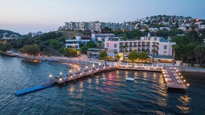 A waterfront hotel with a dock, outdoor seating, and a view of the cityscape.