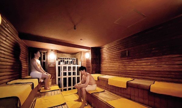 Una sauna con paredes y bancos de madera, y una puerta de cristal que da a una zona de ducha.