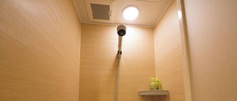 Un cabina de ducha privada con interior de madera, un cabezal de ducha en el techo y dos estantes con artículos de aseo.