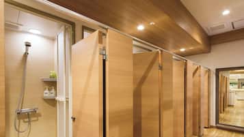 A hotel bathroom with wooden partitions, a shower area, and a mirror reflecting the interior.