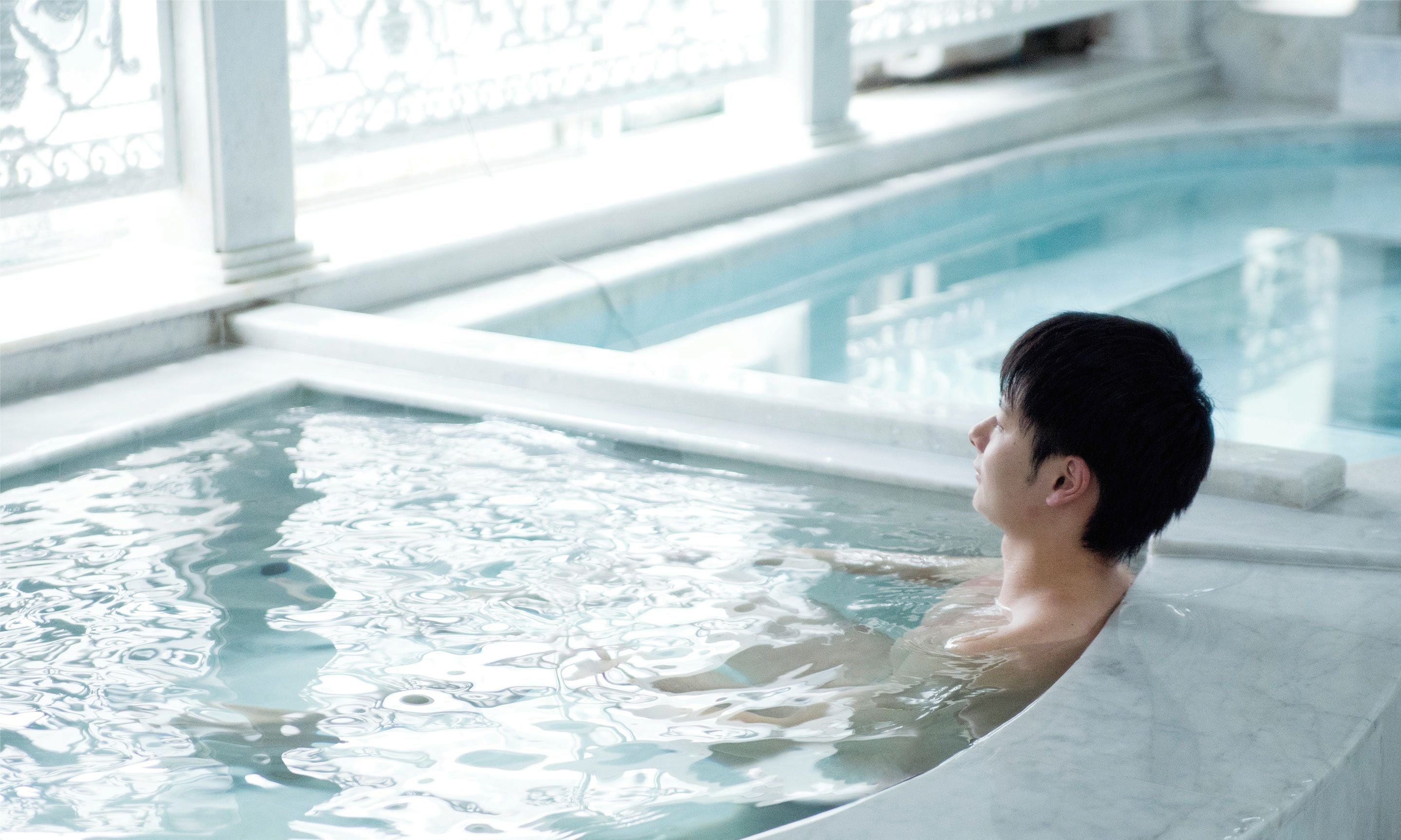 A man in a public bath with a marble interior.