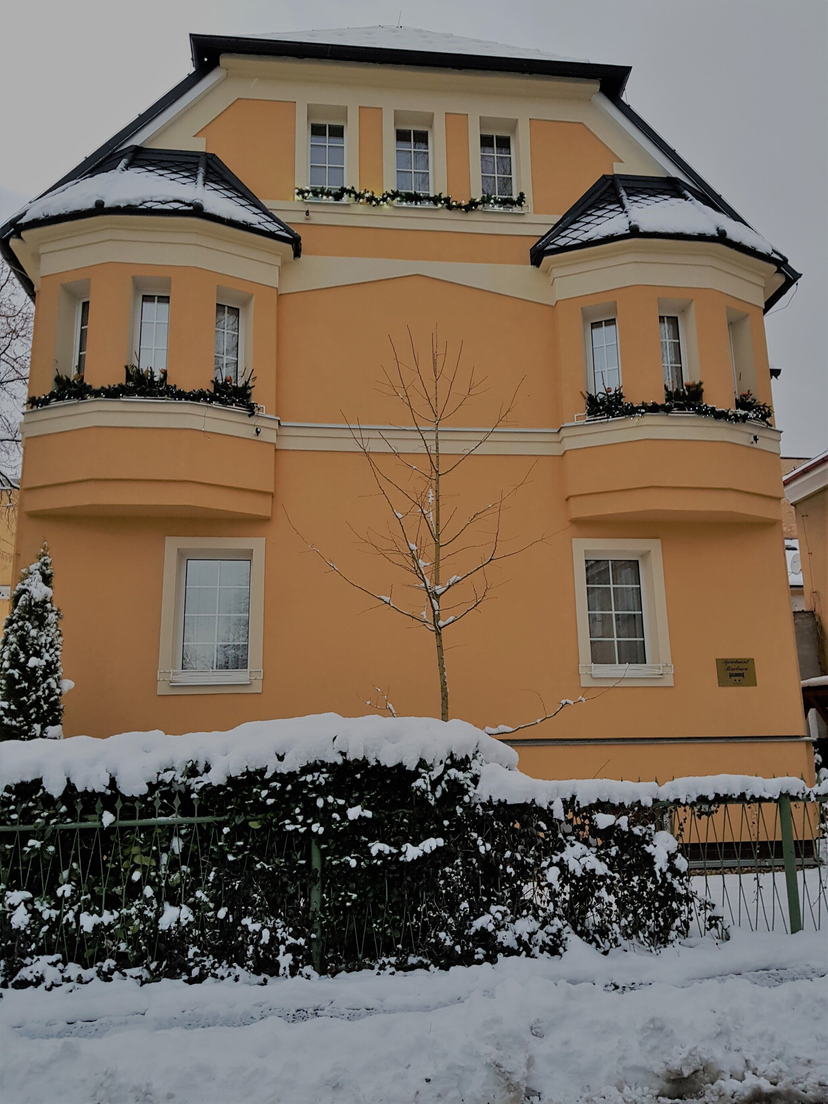 A multi-story building with a symmetrical facade, large windows, and snow-covered balconies.