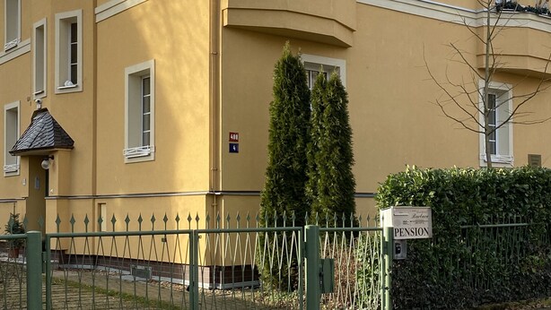 A yellow building with multiple windows and balconies, a green fence, and a sign indicating it is a pension. - Apartment Barbara (Marianske Lazne)