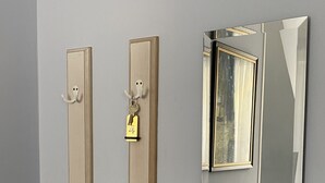 A hallway with two wooden doors, one with a lock and a key, and a mirror reflecting a room with a bed and a nightstand. - Apartment Barbara (Marianske Lazne)