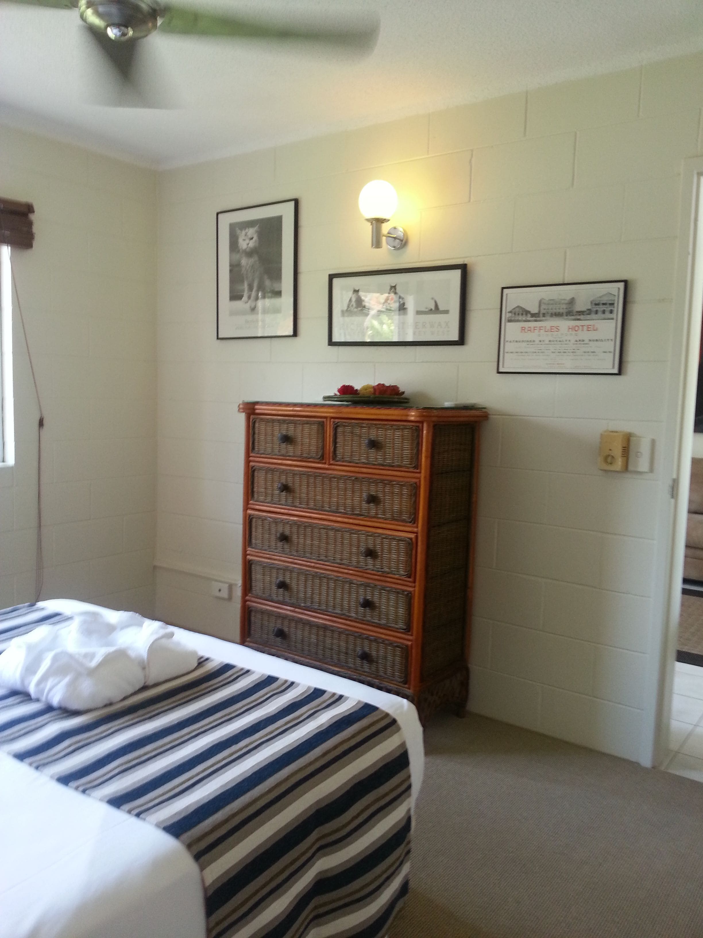 A hotel room with a bed, a dresser, and wall-mounted pictures.