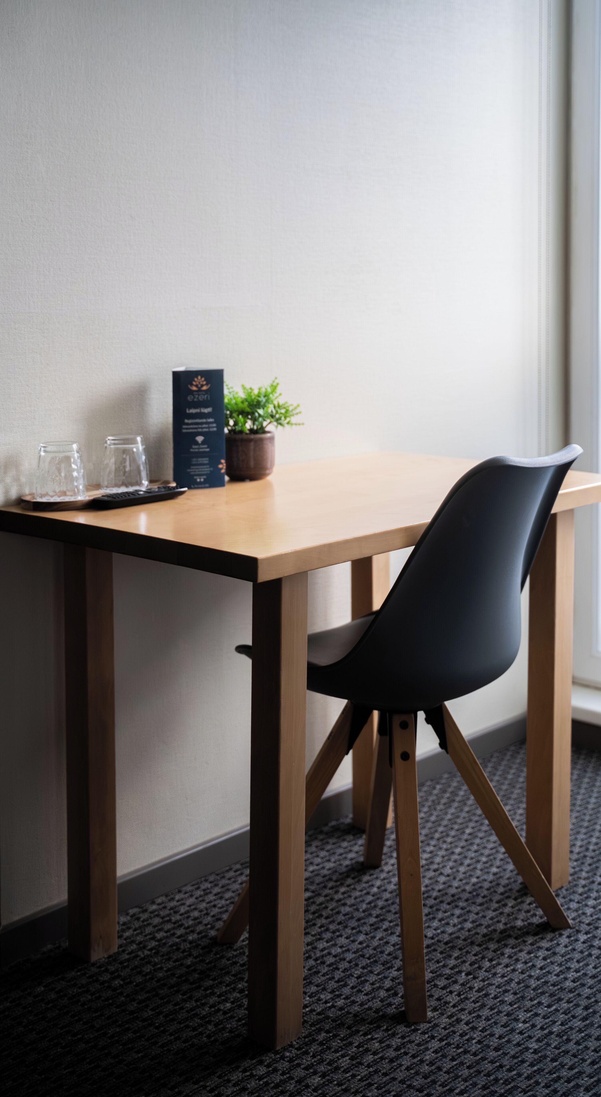 A wooden table with a black chair, a potted plant, and a box labeled "ezer."