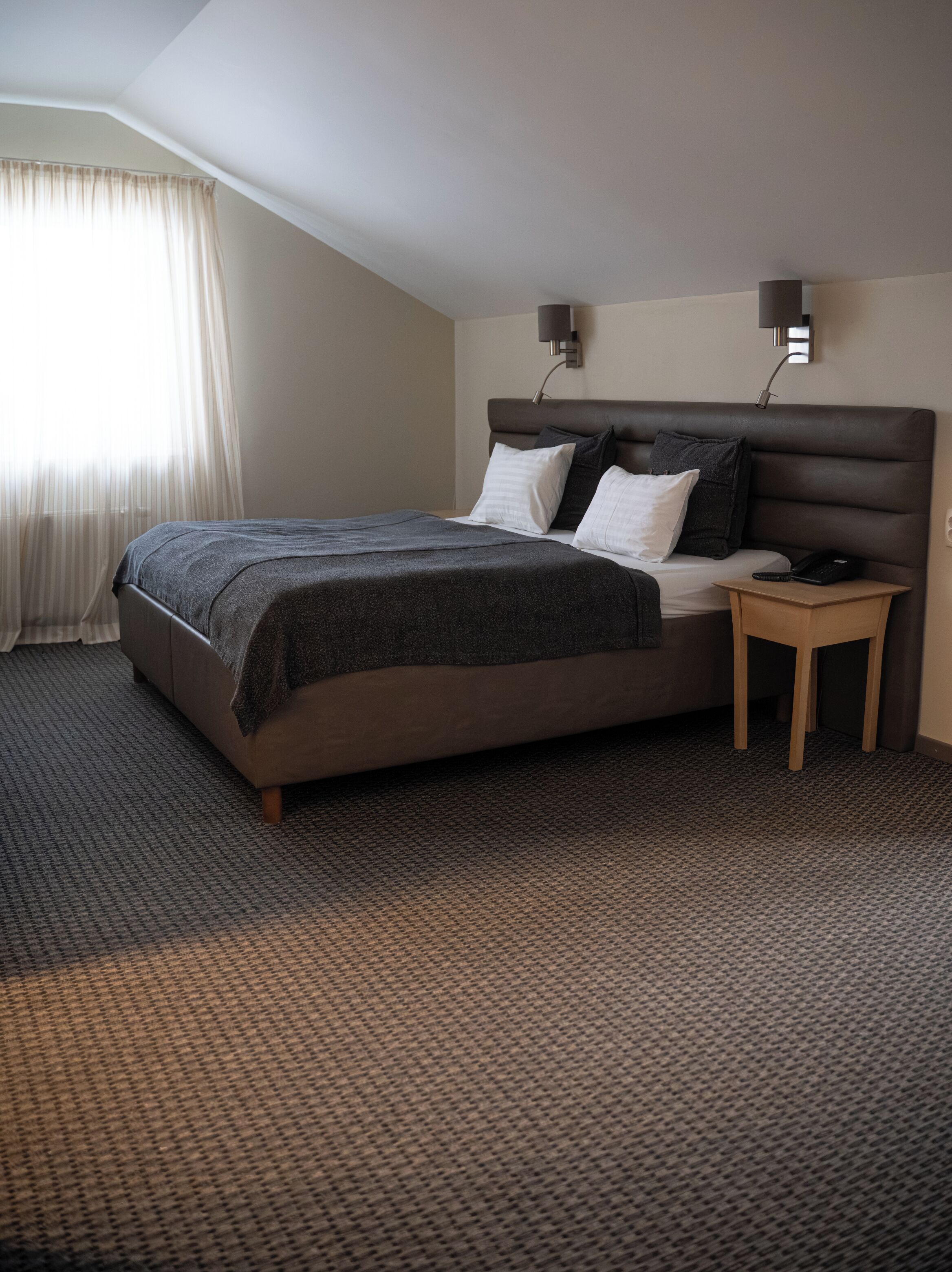 Une chambre d’hôtel moderne avec un grand lit, une table de chevet et une petite table à côté du lit.