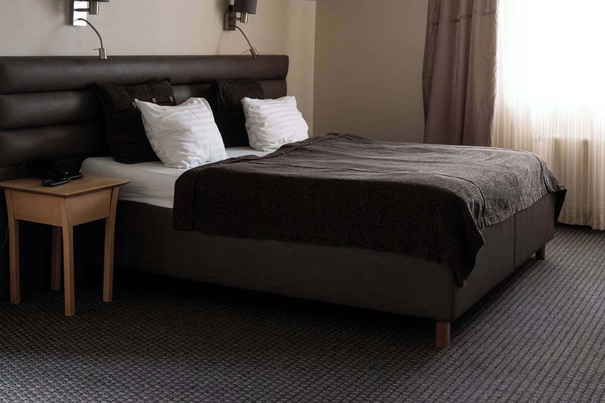 Una habitación de hotel moderna con una cama grande, una mesita de noche y una lámpara.