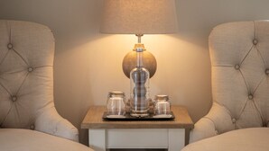A neatly arranged bedroom with two upholstered chairs, a bedside table with a lamp, and a framed certificate on the wall. - The Five Arrows Hotel (Aylesbury)