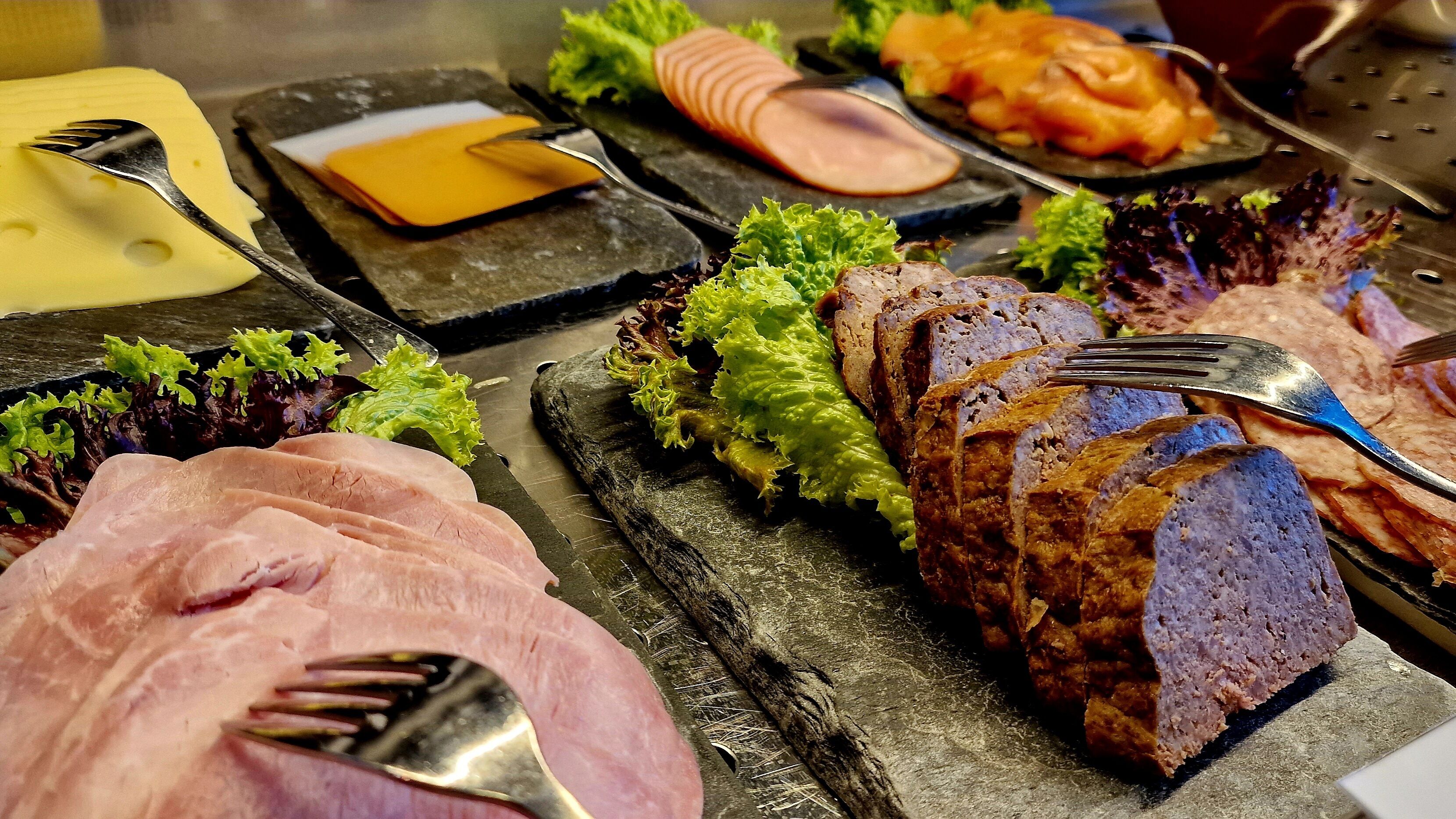 A variety of food items including sliced meats and vegetables on a serving board.