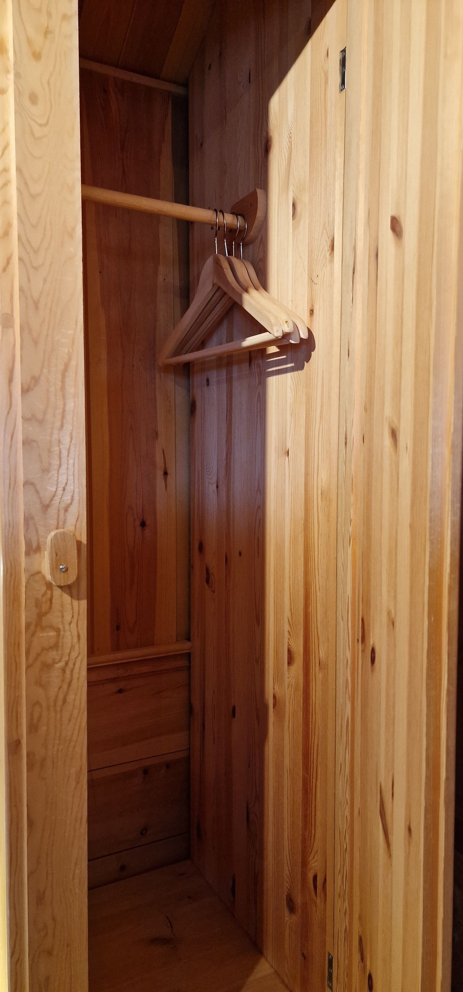 Un placard en bois avec une tringle et un cintre en bois.