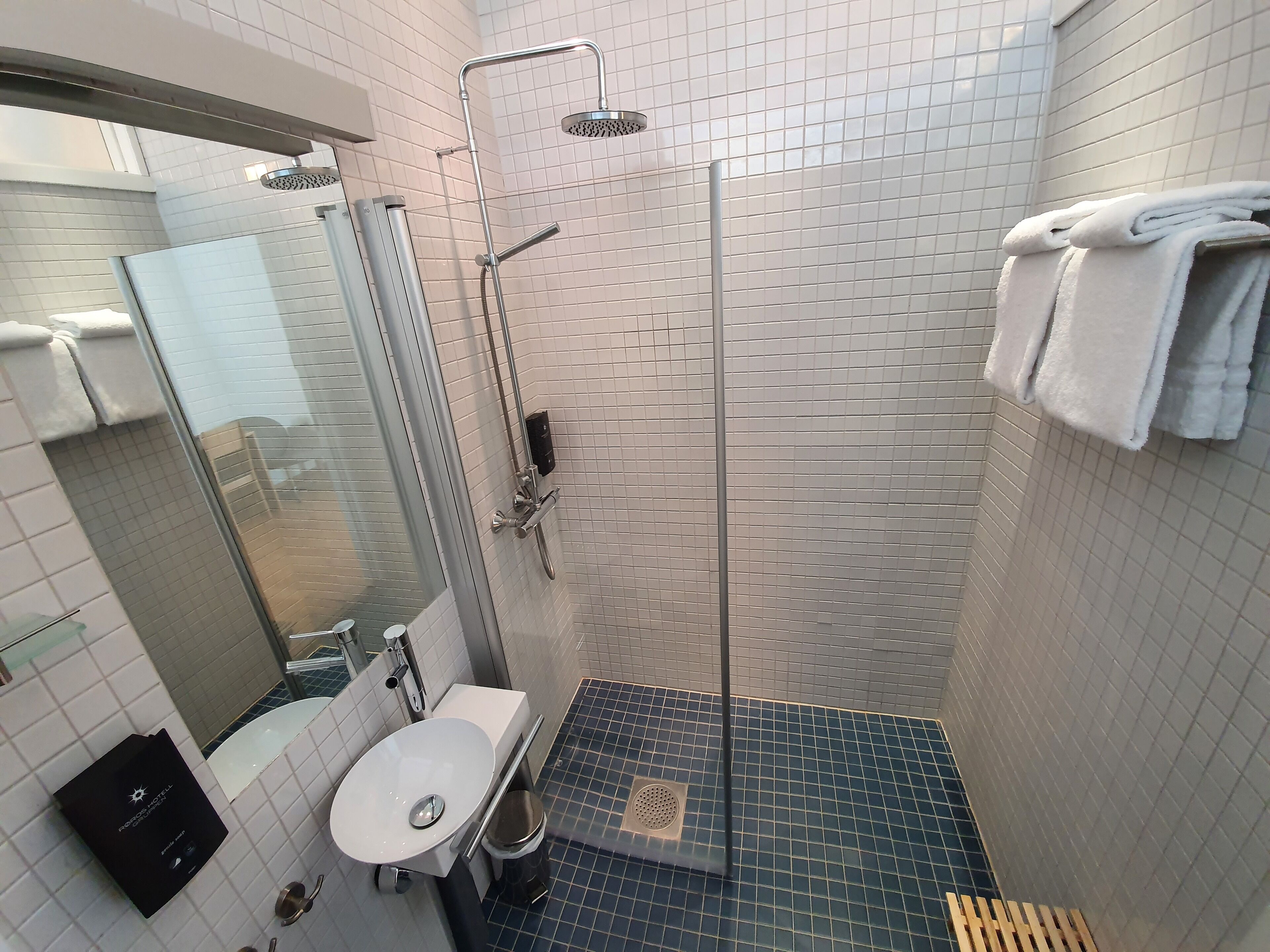 A modern bathroom with a glass shower enclosure, a white sink, and a mirror.
