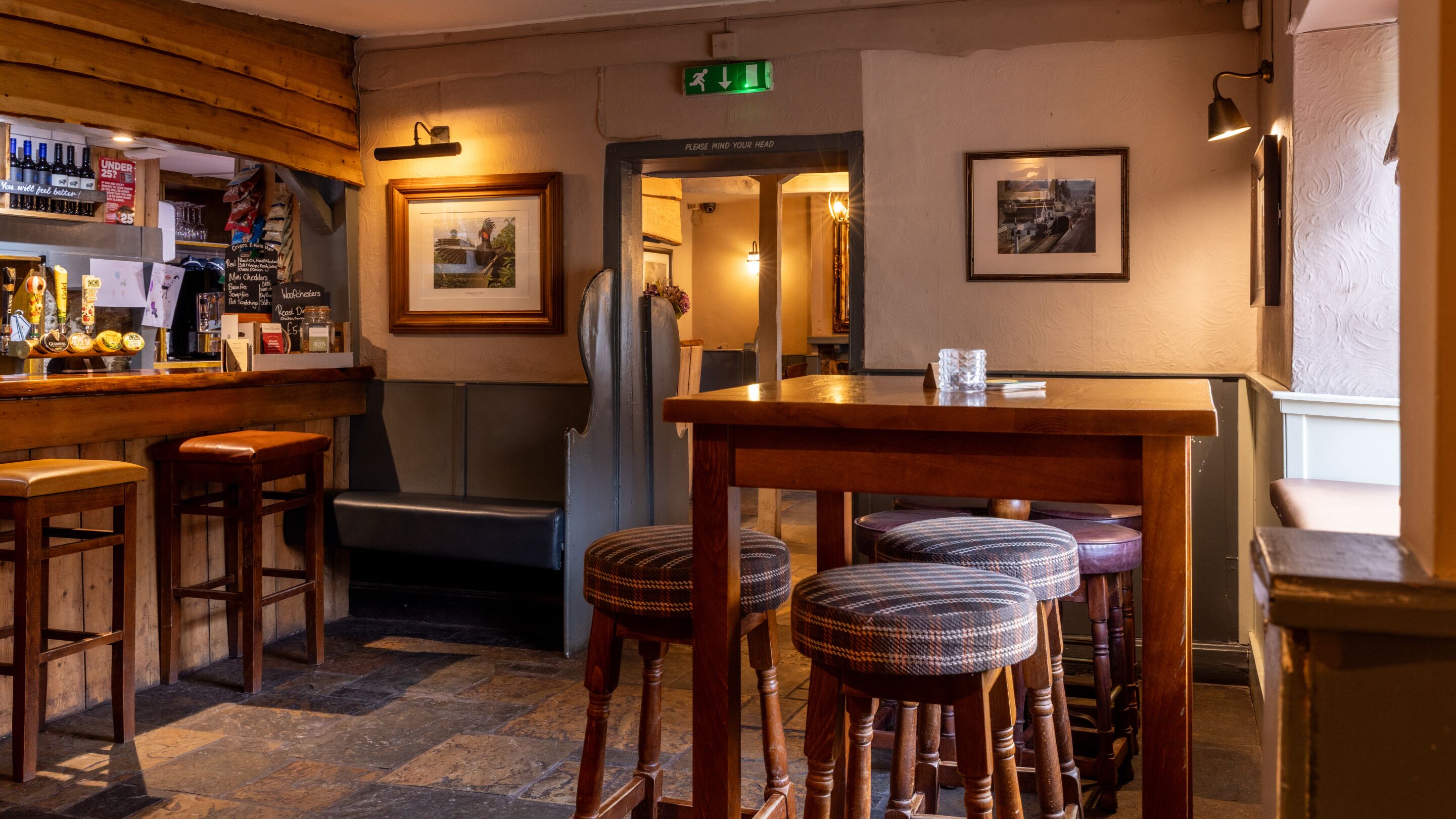 A bar area with stools, a wooden counter, and a framed picture on the wall.