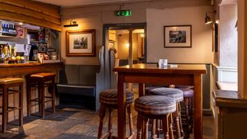 A bar area with stools, a wooden counter, and a framed picture on the wall.