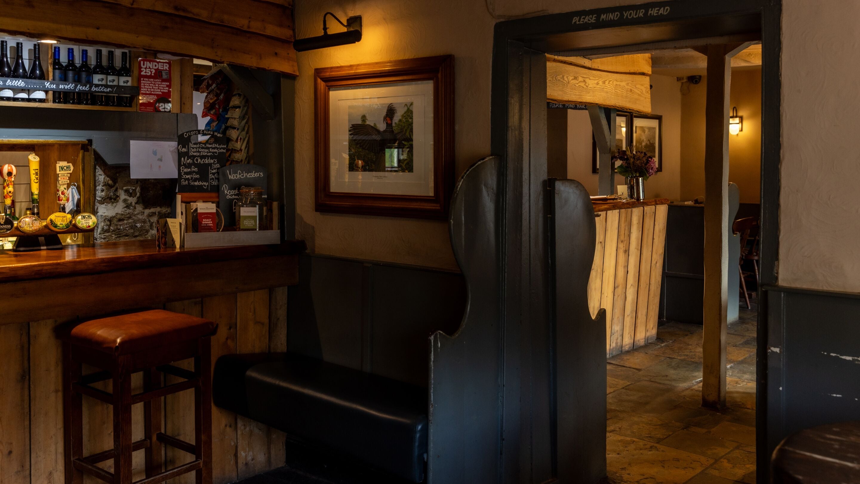 Una zona de bar con taburetes, una barra de madera y un menú en una pizarra.