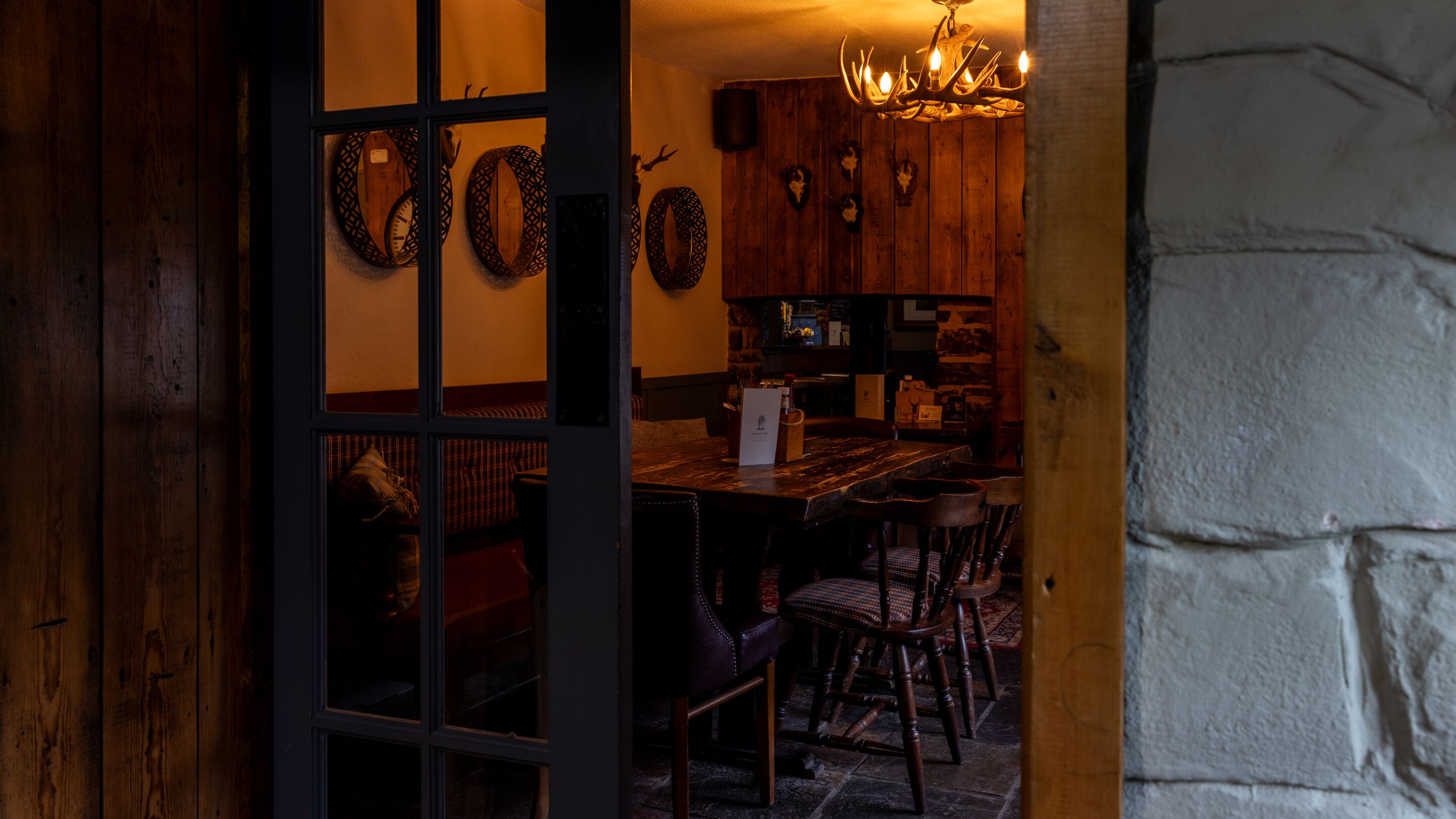 A rustic interior with a wooden dining table, chairs, and a chandelier.