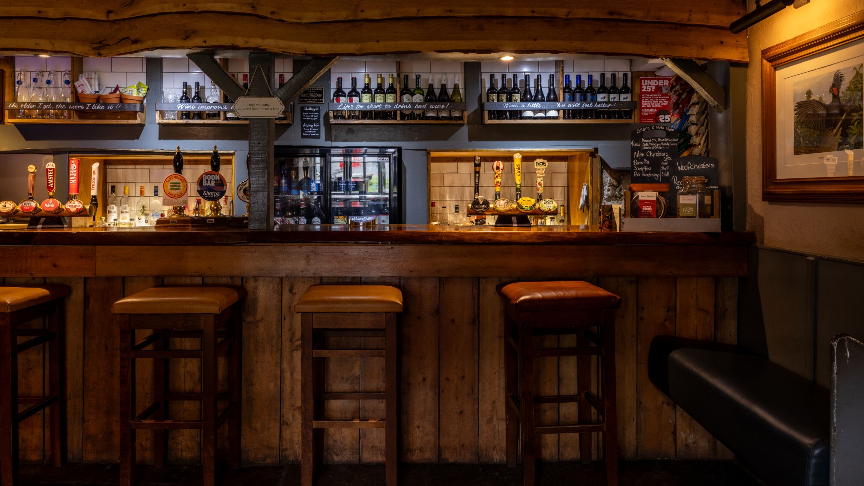 A bar with multiple beer taps, a selection of liquor bottles, and a menu board.
