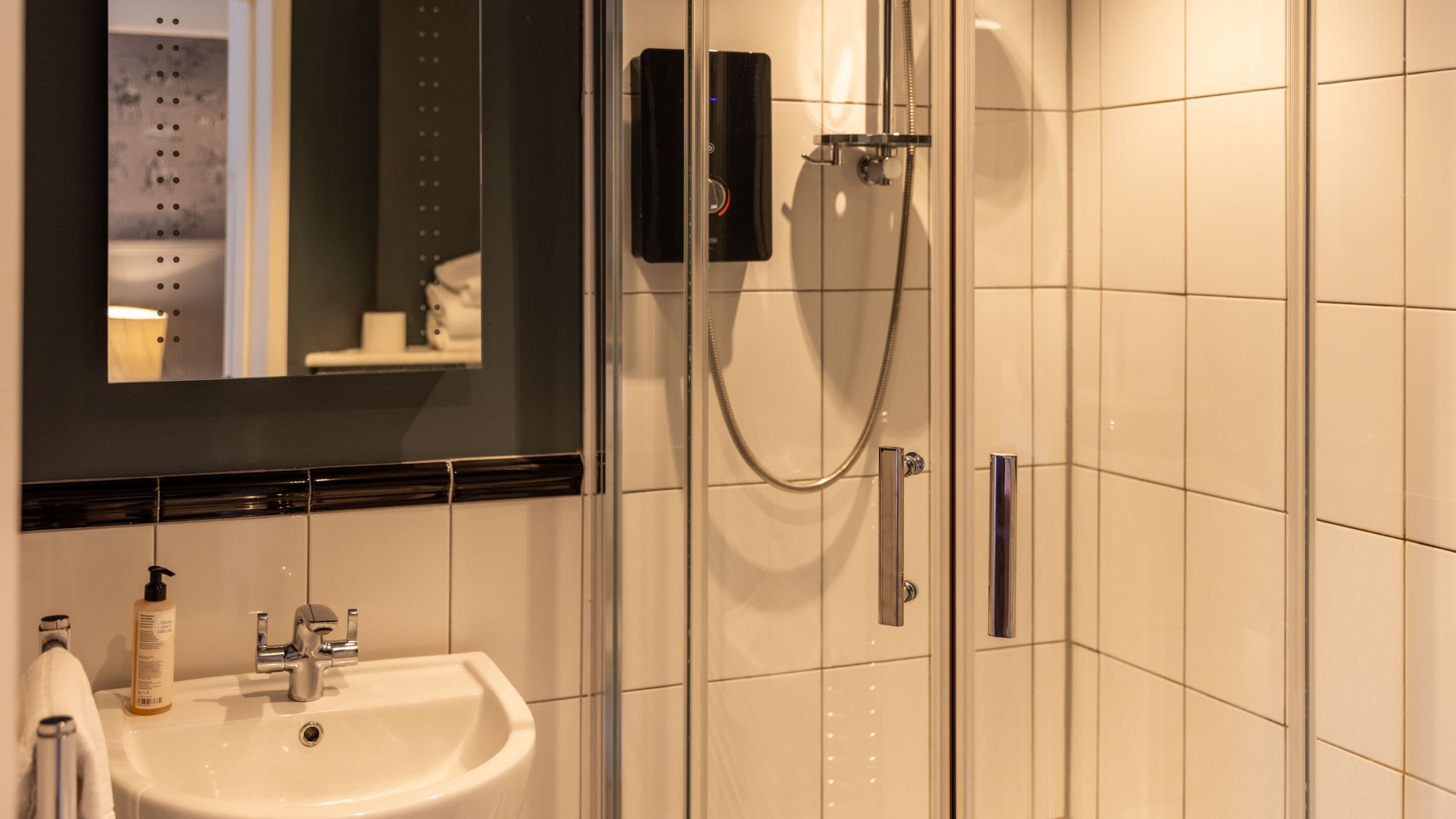 Un baño con lavamanos blanco, un espejo y cabina de ducha.