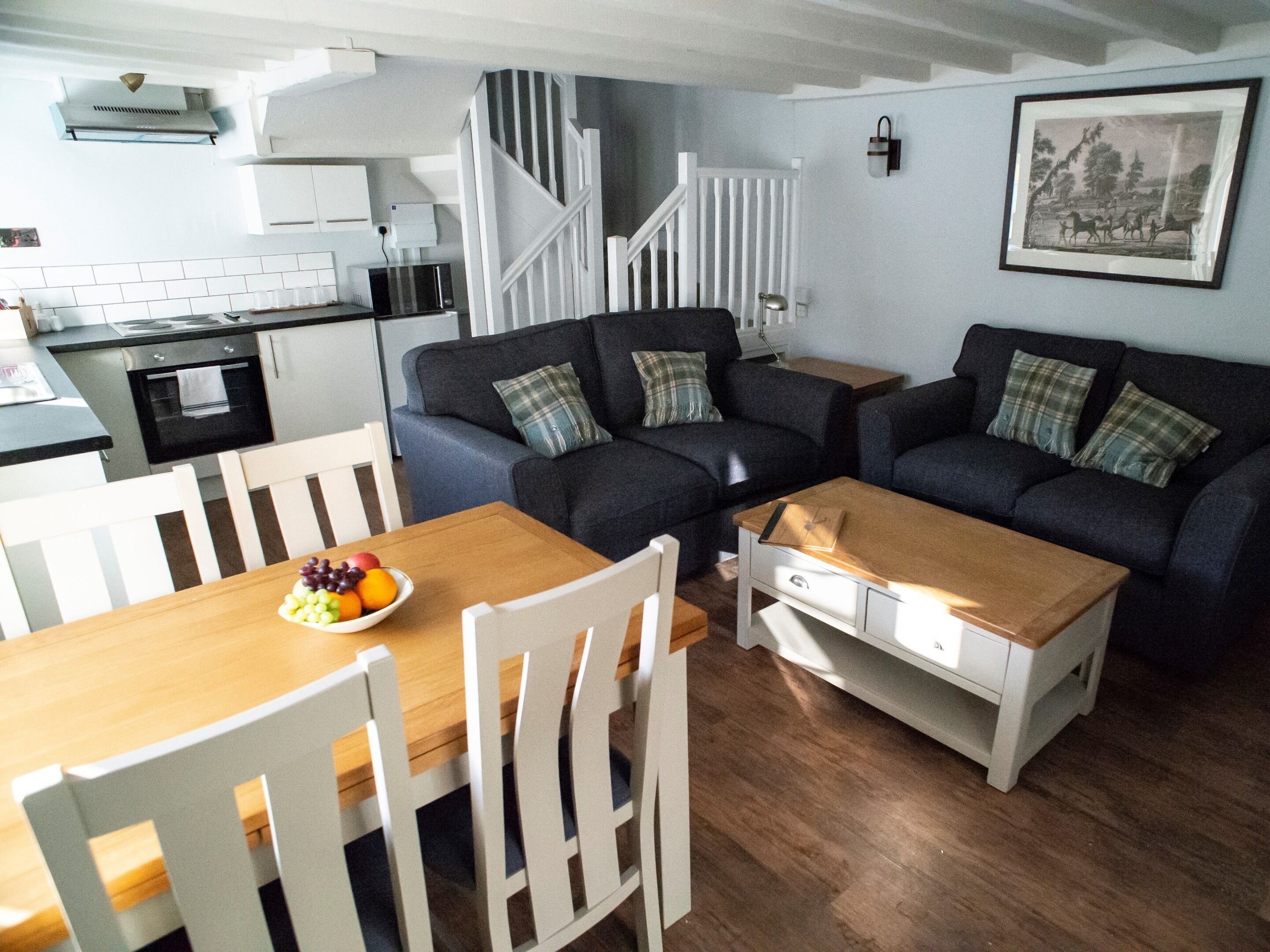 A compact living space with a dining table, two sofas, and a kitchen area.