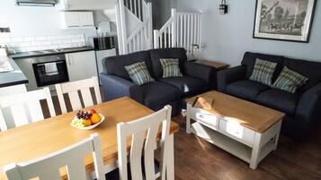 A compact living space with a dining table, two sofas, and a kitchen area.