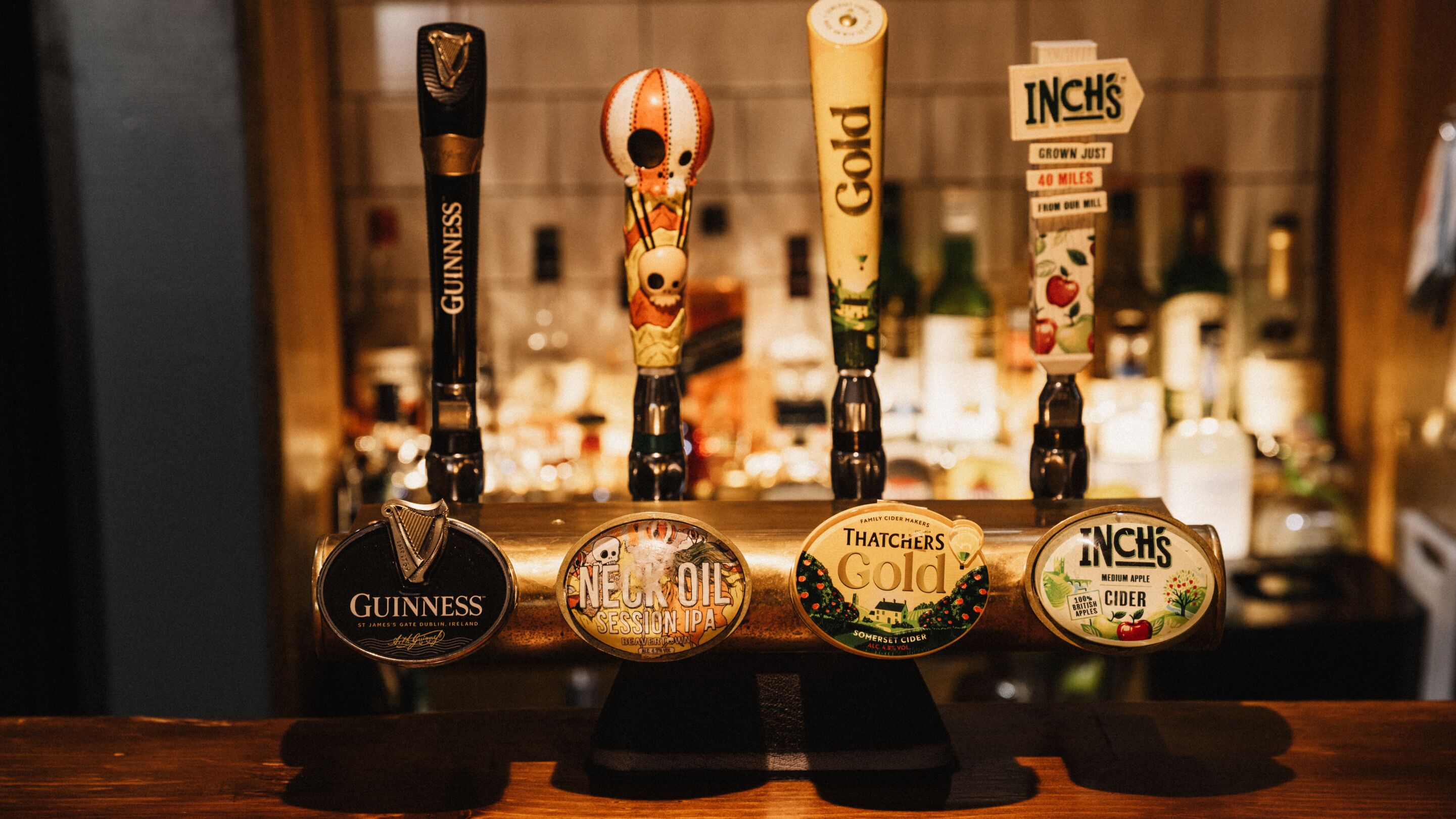 Un bar doté de quatre tireuses, chacune portant le nom d’une marque de bière différente.