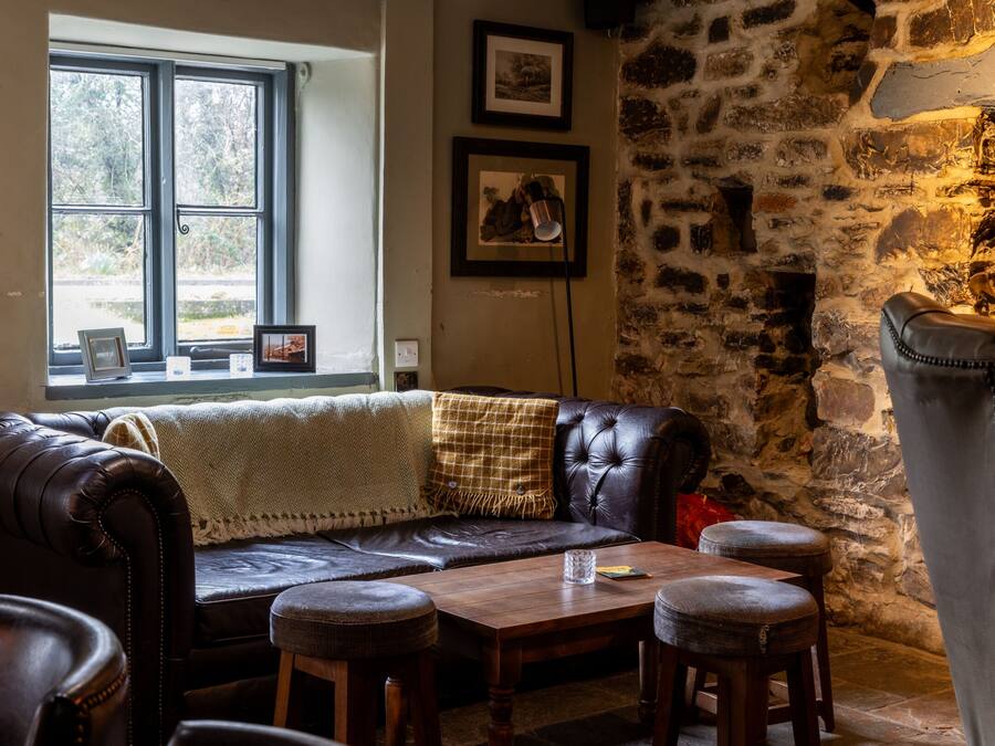 Una habitación acogedora con un sofá de cuero, una mesa de madera y una pared de piedra.
