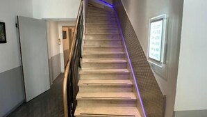 Una escalera con barandilla, un letrero en la pared y una puerta al final.