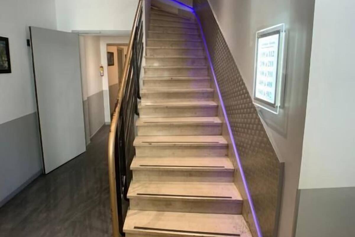 A staircase with a handrail, a wall-mounted sign, and a door at the bottom.